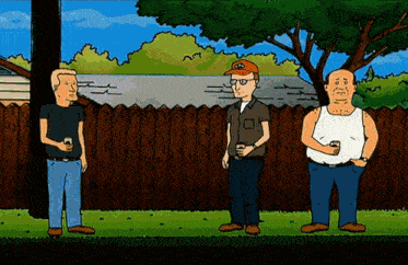 three men standing in front of a wooden fence with one wearing a hat that says ' king of the hill '