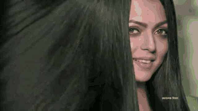 a woman with long black hair is smiling and covering her face .