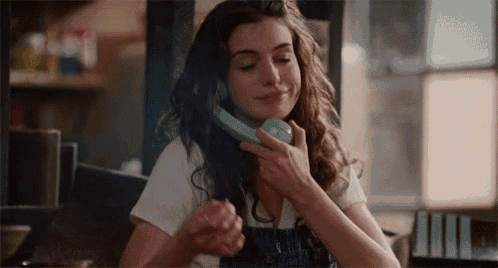 a woman is talking on a telephone and smiling .