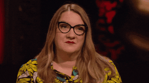a woman wearing glasses and a floral shirt is making a face