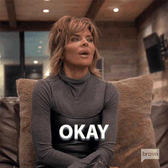 a woman sitting on a couch with the word okay written on her face