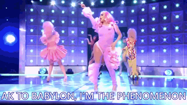 a group of drag queens are dancing on a stage with the words ak to babylon , i 'm the phenomenon .
