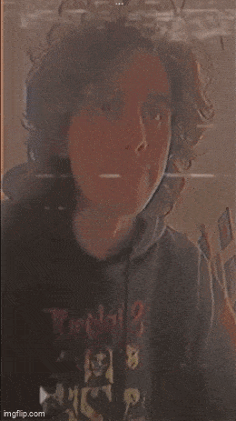 a man with curly hair is taking a selfie in a mirror .