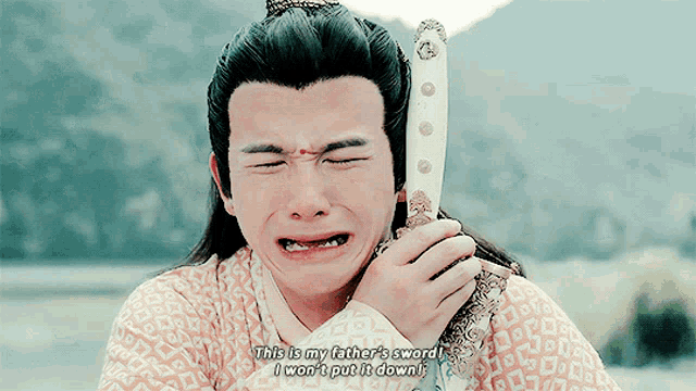 a man is crying while holding a sword in his hand