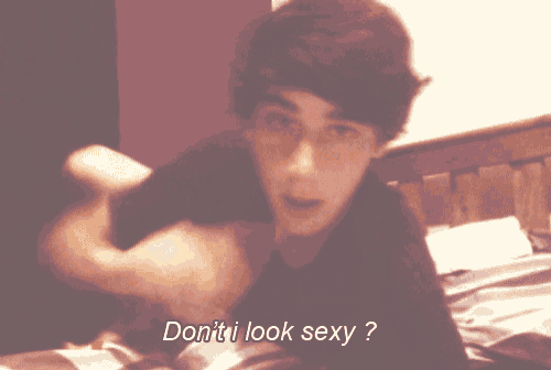 a young man laying on a bed with the words " do n't i look sexy " below him