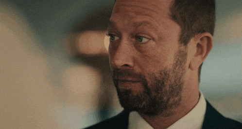 a man with a beard is wearing a suit and a white shirt