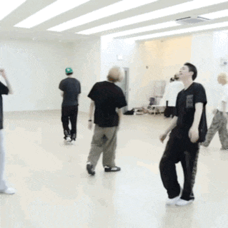 a man in a black shirt is kneeling on the floor in a dance studio