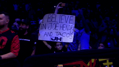 a person is holding a sign that says i believe in joe hendry and tacos jh