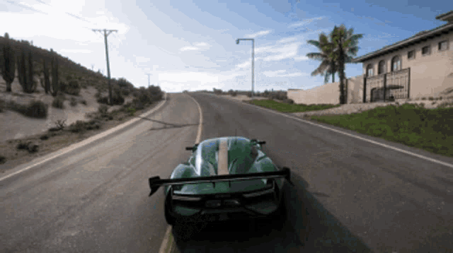 a green sports car is driving down a road in the desert