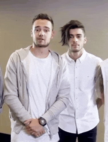 two men are standing next to each other in a room . one of the men is wearing a watch .