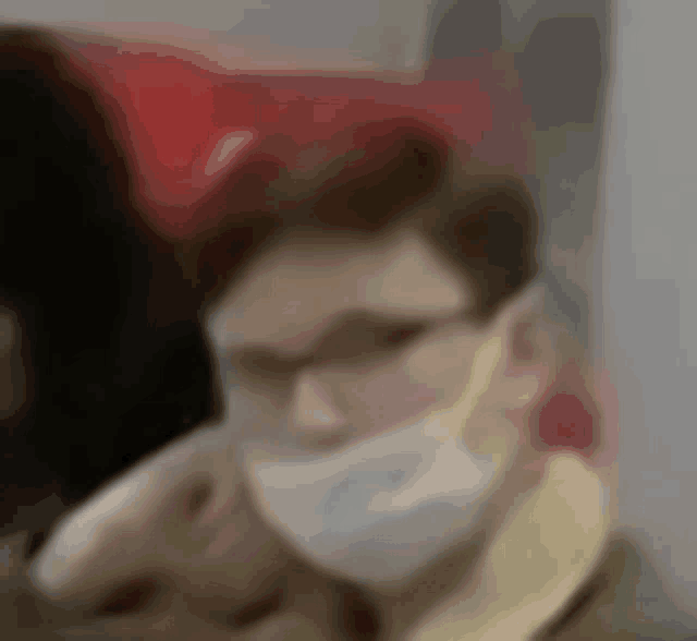 a man wearing a mask and glasses is sitting in a chair .