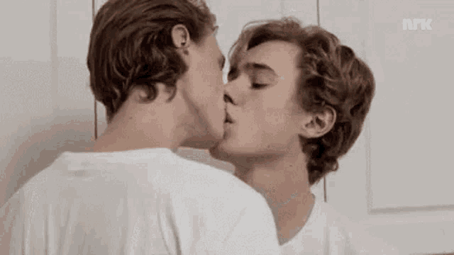 two young men are kissing each other in front of a door .