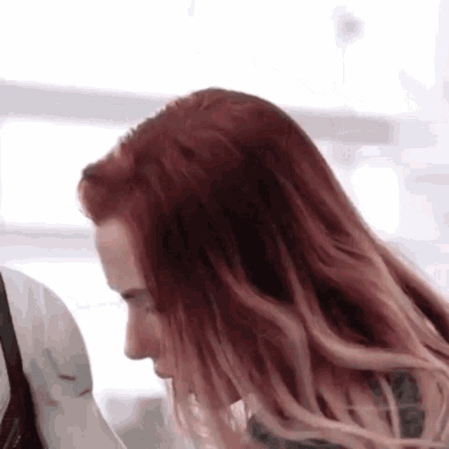 a woman with long red hair is standing next to a man in a white jacket .