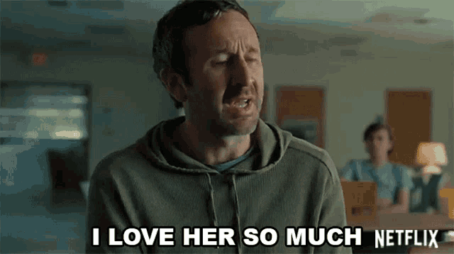 a man in a hoodie is saying `` i love her so much netflix '' while sitting at a table .