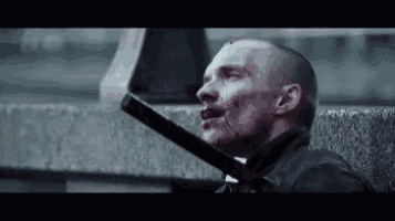 a man with blood on his face is holding a sword in his hand .