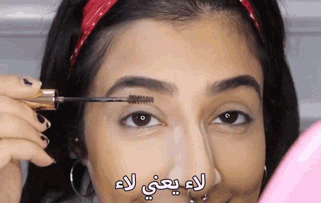 a woman is applying mascara to her eyebrows with arabic writing on the bottom