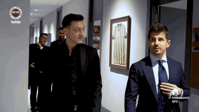 a group of men are walking down a hallway with a youtube logo on the wall