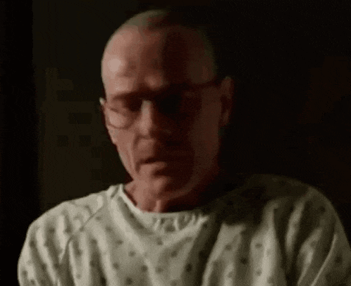 a man in a hospital gown is crying and looking down .