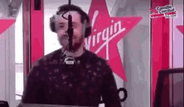 a man wearing headphones is standing in front of a microphone in a radio station .