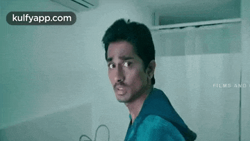 a man in a blue shirt is making a funny face in a room .