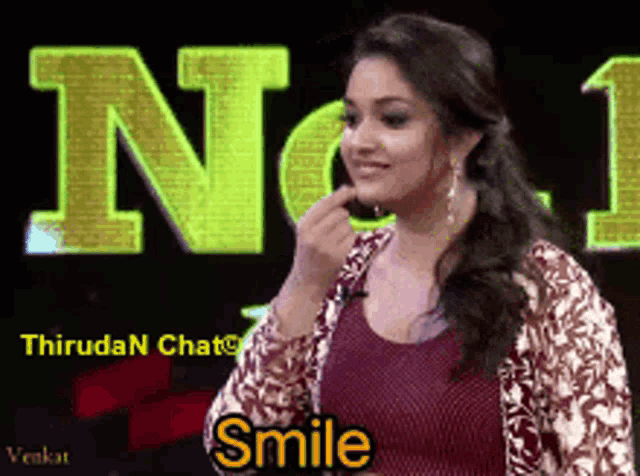 a woman is smiling in front of a sign that says thiruda n chat