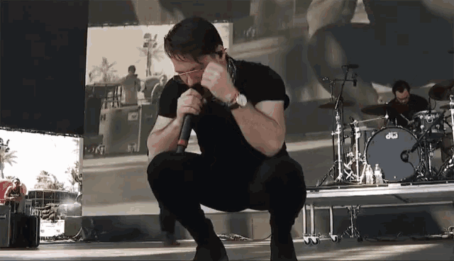 a man singing into a microphone with a drum set in the background that says dw