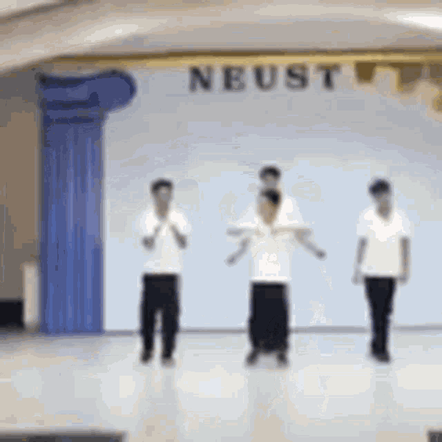 a group of people are standing on a stage with the word neust above them