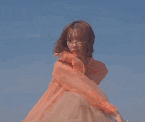 a woman in a pink dress is dancing in front of a blue sky .