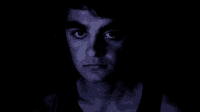 a close up of a man 's face in the dark with his eyes closed