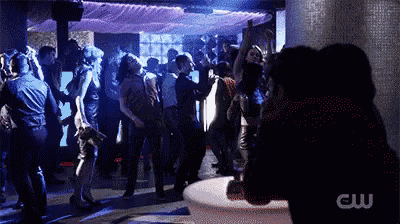 a crowd of people are dancing in a club with a cw logo in the corner