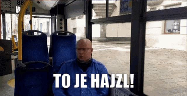 a man sitting on a bus with the words to je hajzl written above him