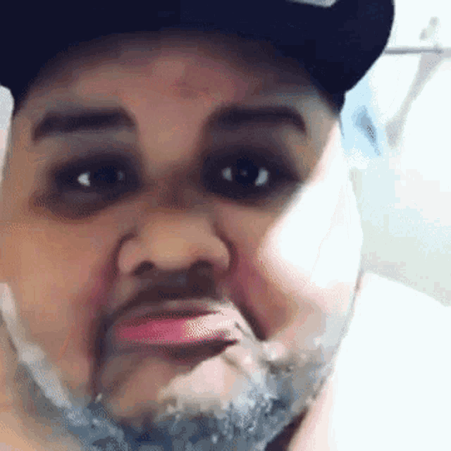 a man with a beard is wearing a hat and looking at the camera .