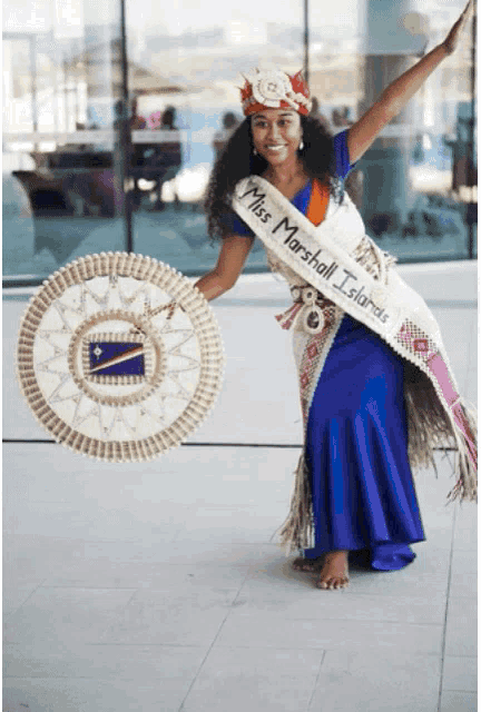 a woman wearing a sash that says miss marshall islands is holding a fan
