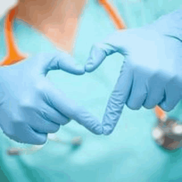 a nurse is making a heart shape with her hands in blue gloves .