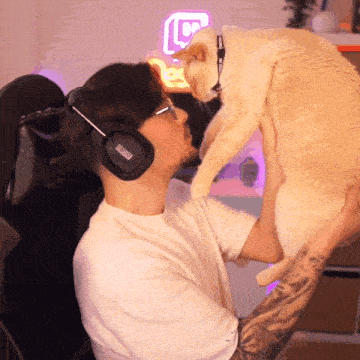 a man wearing headphones with the word dxracer on them holds a cat