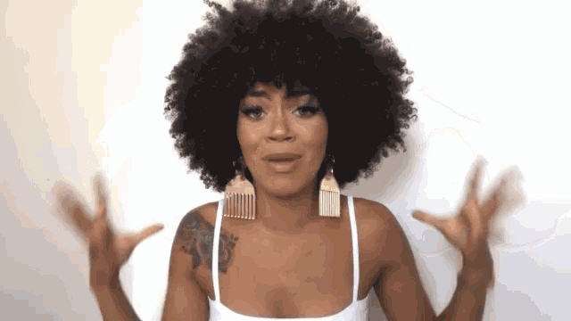 a woman wearing a white tank top and earrings with combs in her hair