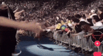 a crowd of people behind a fence with a bull logo
