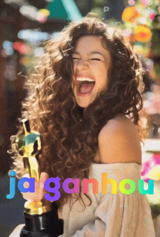 a woman with curly hair is holding an oscar statue and laughing with the words jaga ganhou written below her