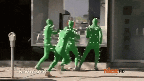 a group of people in green costumes are walking down a street in front of a store that says nick hd