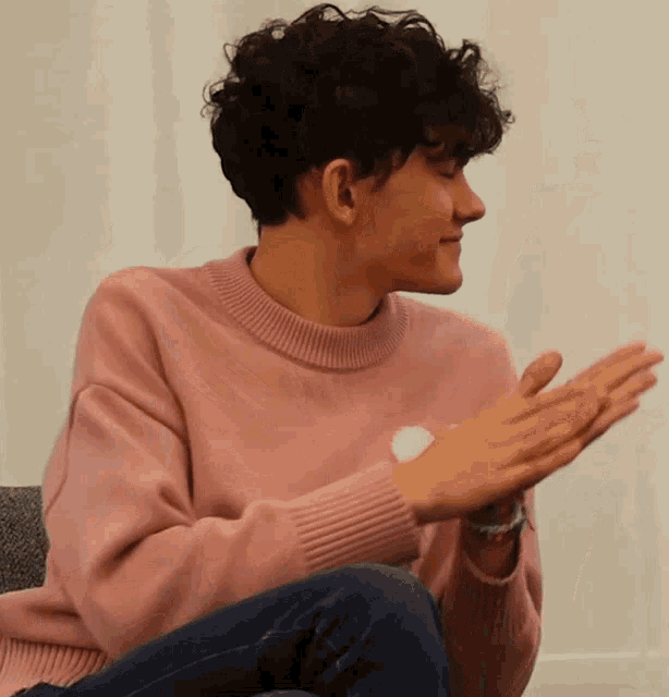a person wearing a pink sweater is clapping their hands