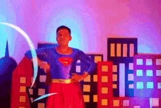 a man dressed in a superman costume is standing in front of a city .
