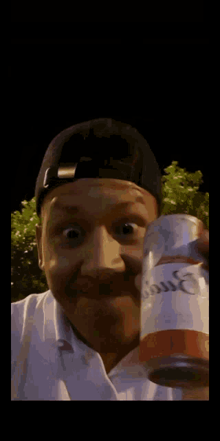 a man wearing a hat is holding a can of coca cola