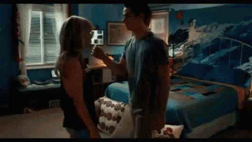 a man and a woman are kissing in a bedroom with a bed .