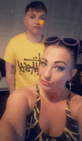 a man in a yellow stussy shirt stands next to a woman in a swimsuit