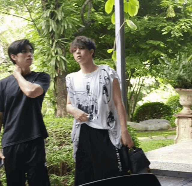 a man in a black shirt stands next to a man in a white shirt with a picture of a woman on it