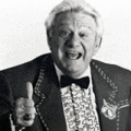 a man in a tuxedo and bow tie is giving a thumbs up sign .