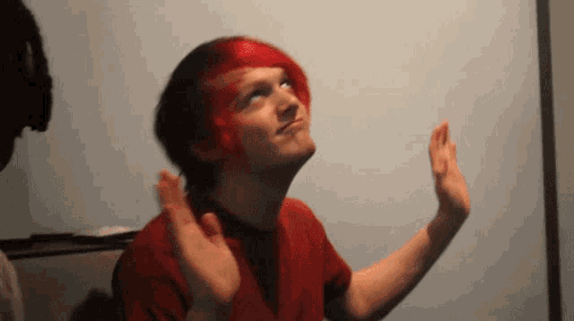 a man with red hair and a red shirt looks up at something