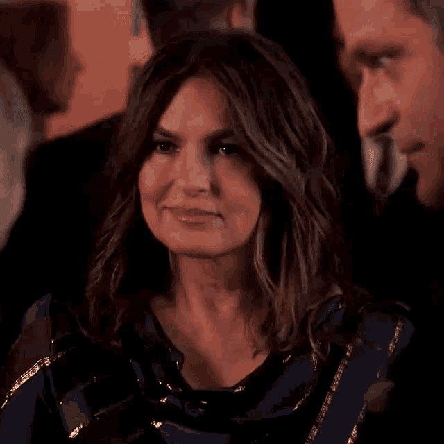 a woman is smiling and looking at a man in a suit .