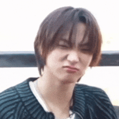 a young man with short hair is making a funny face while wearing a sweater .