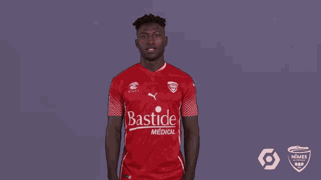 a man in a red bastide medical jersey holds his fist in the air